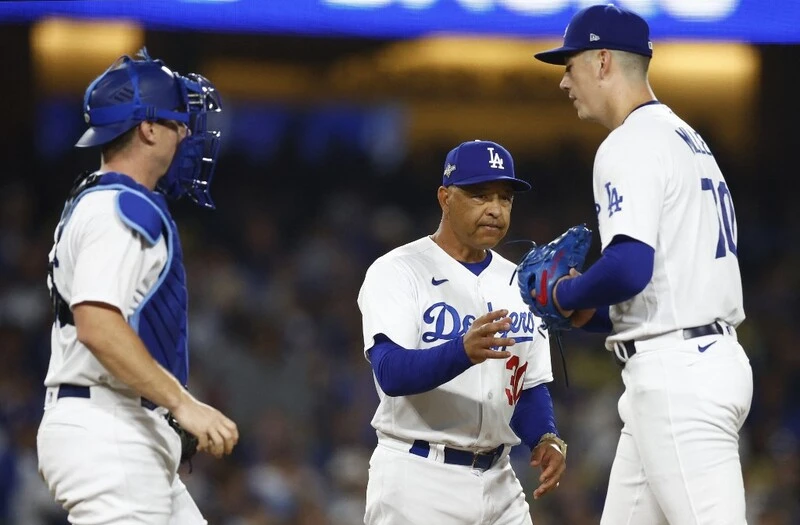 Dodgers head coach, Dave Roberts, instructs two of his players.