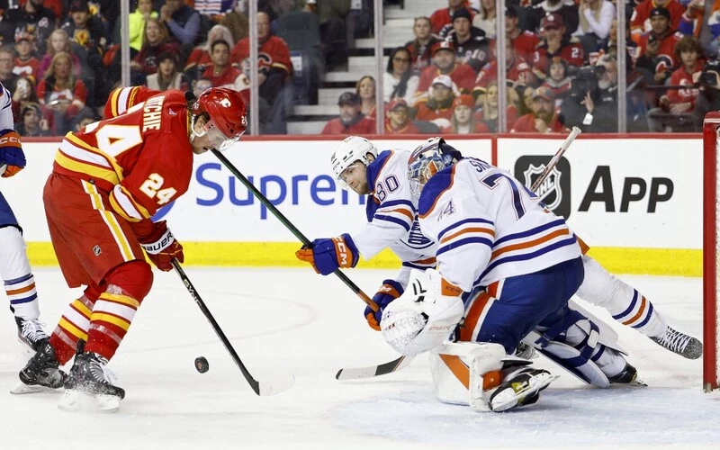 Brett Ritchie #24 of the Calgary Flames takes a shot against Stuart Skinner #74 and Markus Niemelainen #80 of the Edmonton Oilers in the third period at the Scotiabank Saddledome on December 27, 2022, in Calgary, Alberta, Canada. The Flames vs Oilers Odds are already set.