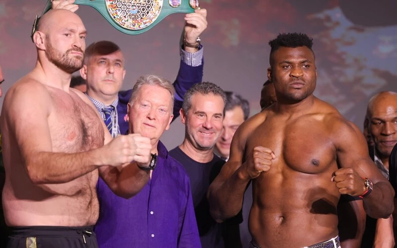 Britain's Tyson Fury (L) and Cameroonian-French Francis Ngannou react during their weigh-in on the eve of their bout in Riyadh on October 27, 2023. The Fury vs Ngannou Prediction is here.